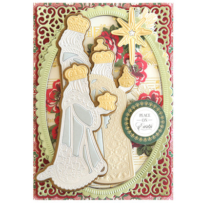 A decorative holiday card featuring three crowned figures, reminiscent of the Three Wise Men 3D Dies, holding gifts under the Star of Wonder, with floral designs and a "Peace on Earth" message. The card boasts intricate border detailing in festive green and red.