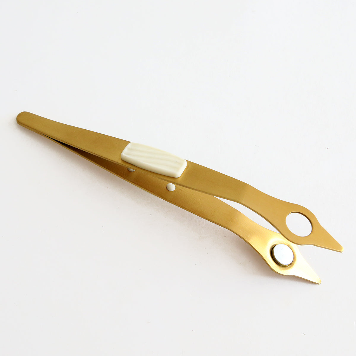 A pair of Magnetic Tweezers on a clean white surface.
