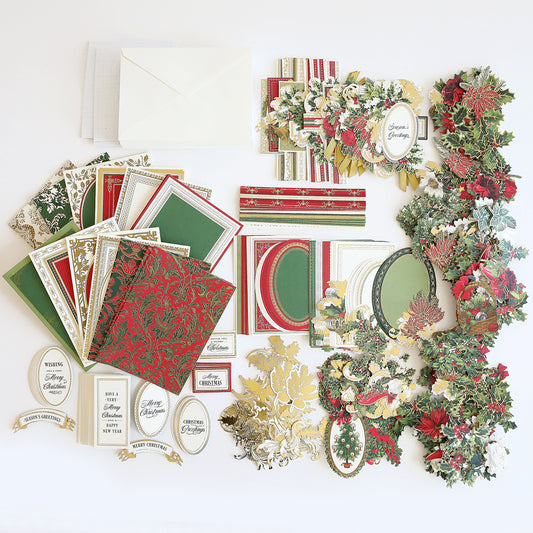 An assortment of items in the Christmas Greetings Card Making Kit, including envelopes, cards, decorative papers, various greeting labels, and festive embellishments for crafting exquisite handmade Christmas cards, all arranged neatly on a white surface.