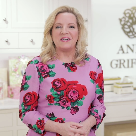 A woman in a pink floral dress standing in front of a kitchen.