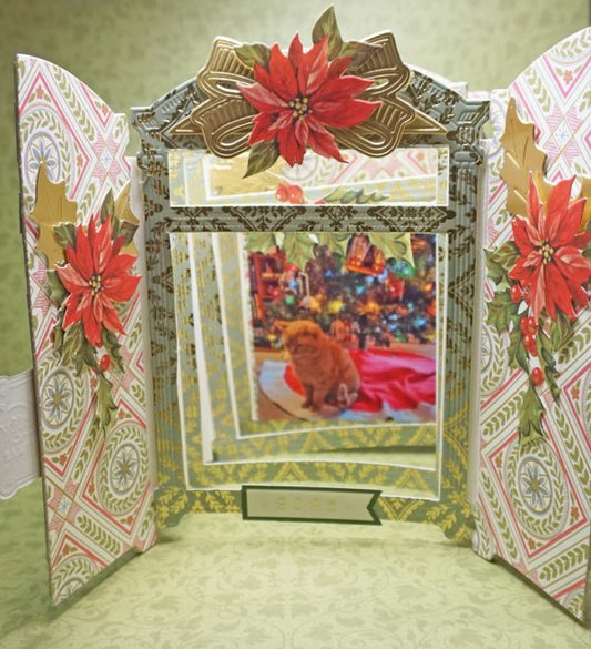 A festive tri-fold card from Holiday Sales 2025 features poinsettias and frames a photo of an orange cat by a decorated Christmas tree, perfect for holiday celebrations.