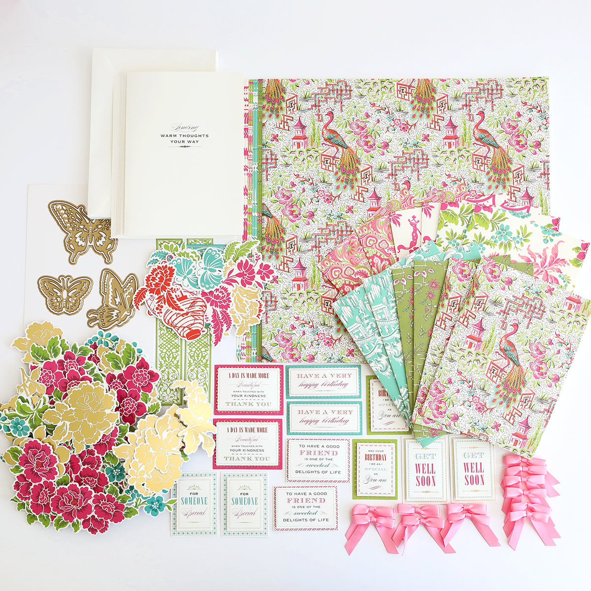 The Chinoiserie Papercrafting Kit with Dies features floral and patterned paper, die cuts, cards, envelopes, gold butterflies, and pink ribbons beautifully arranged on a white background.