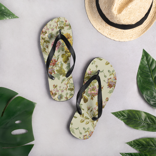 Bright flip-flops sit on a light surface, paired with a straw hat and vivid green leaves.