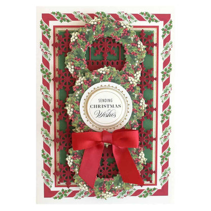 a christmas card with a wreath and ribbon.