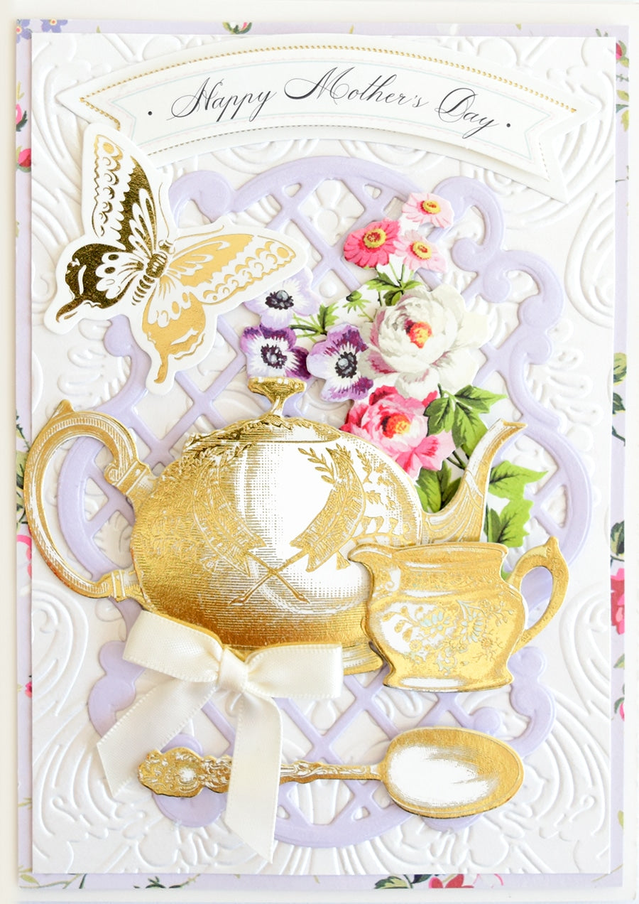 a card with a gold teapot and flowers.