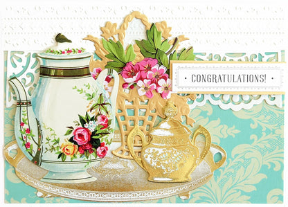 a card with a tea pot and a basket of flowers.