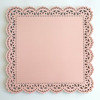 a pink doily frame on a white wall.