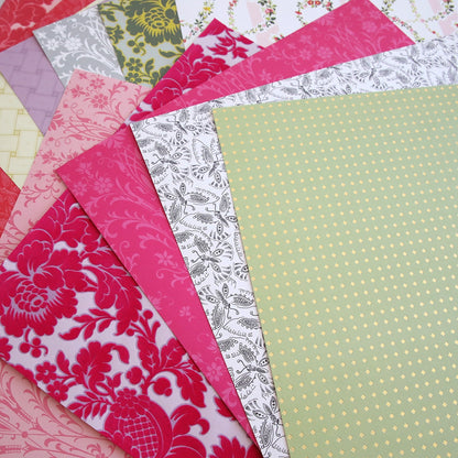A pile of Grace 12x12 Cardstock with different patterns on them.