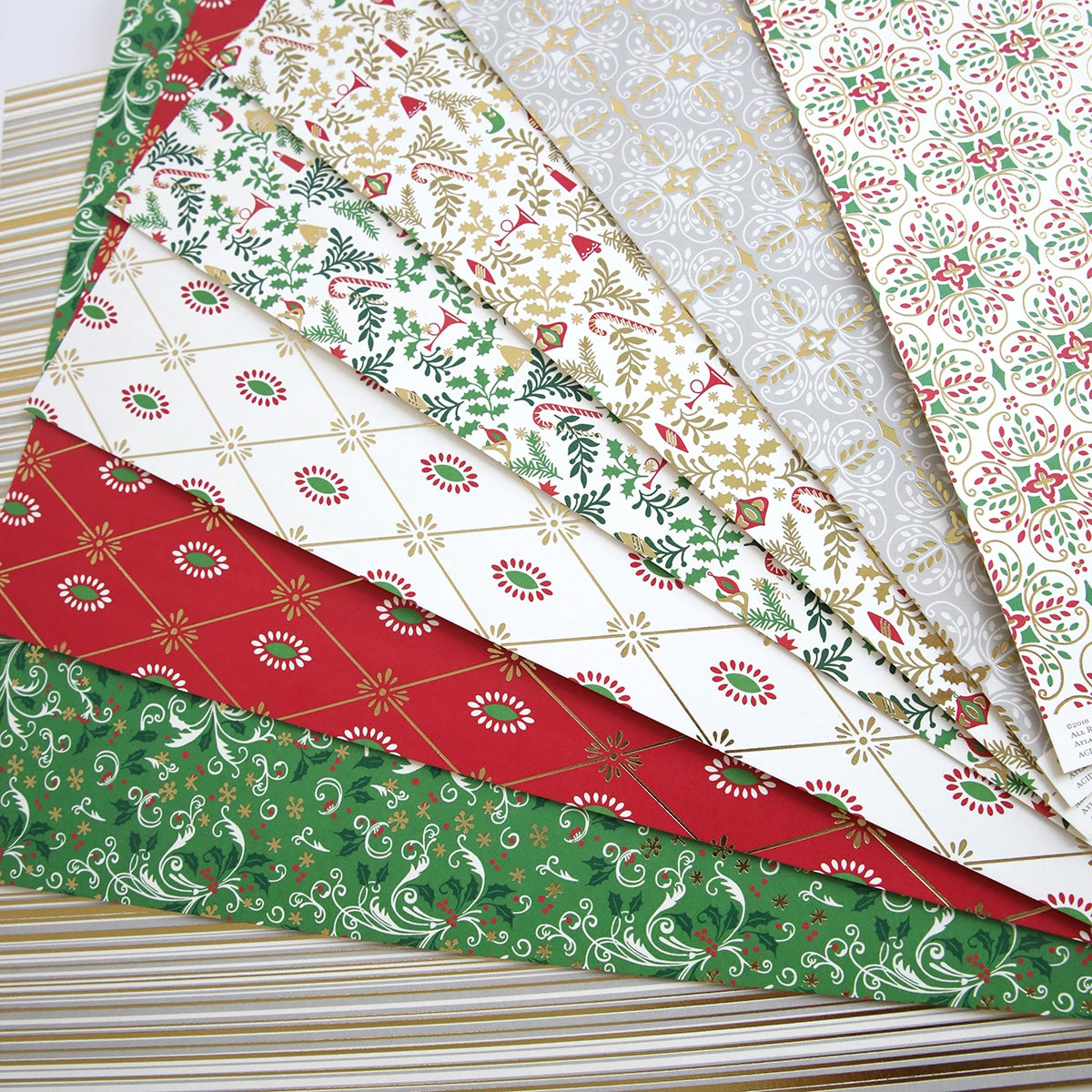 a stack of Christmas 12x12 Cardstock with red, green, and gold designs.