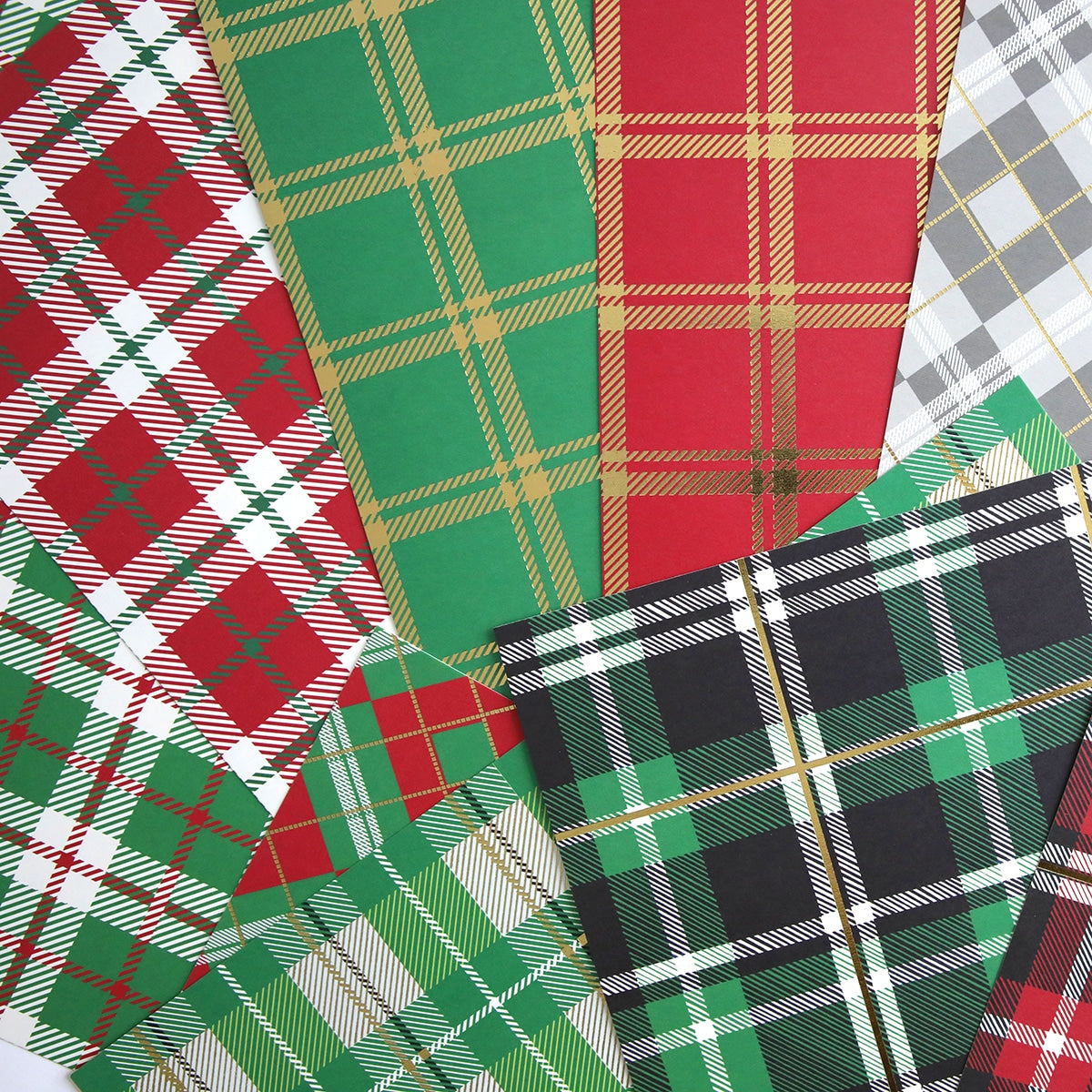 a bunch of Christmas Plaid 12x12 Cardstock papers on a white surface.