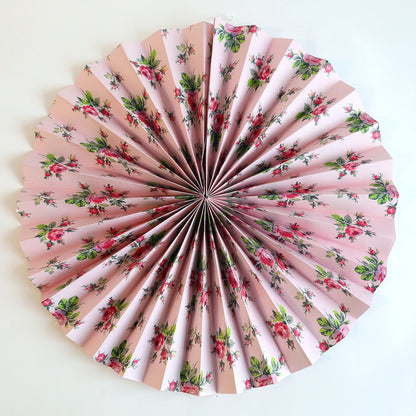 a pink paper fan with red flowers on it.