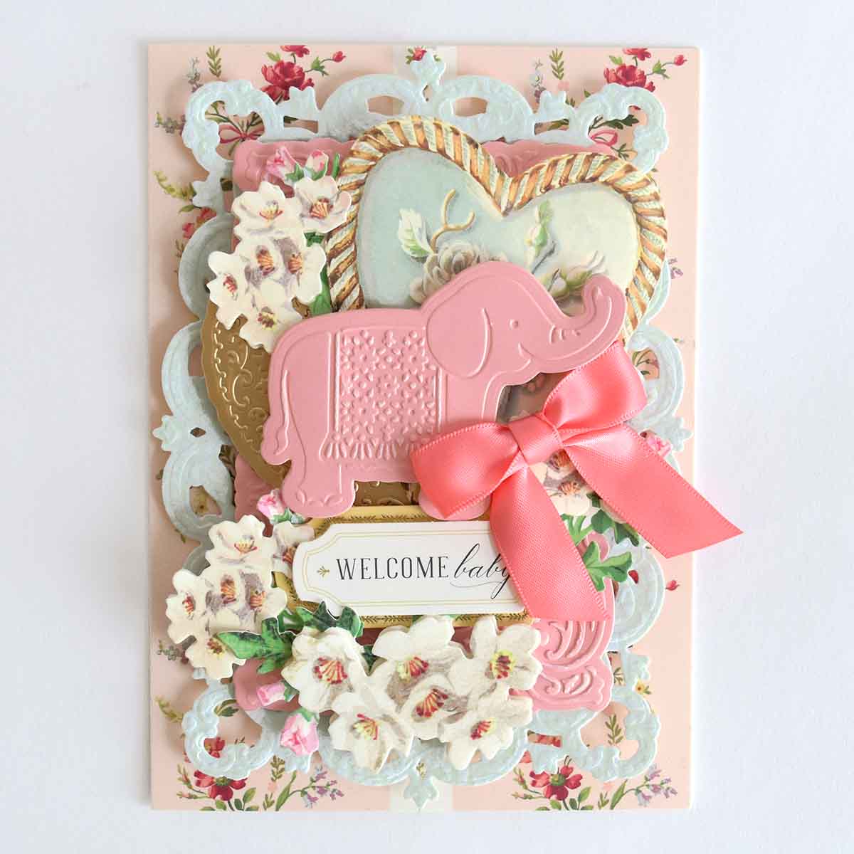 a welcome card with a pink elephant and flowers.