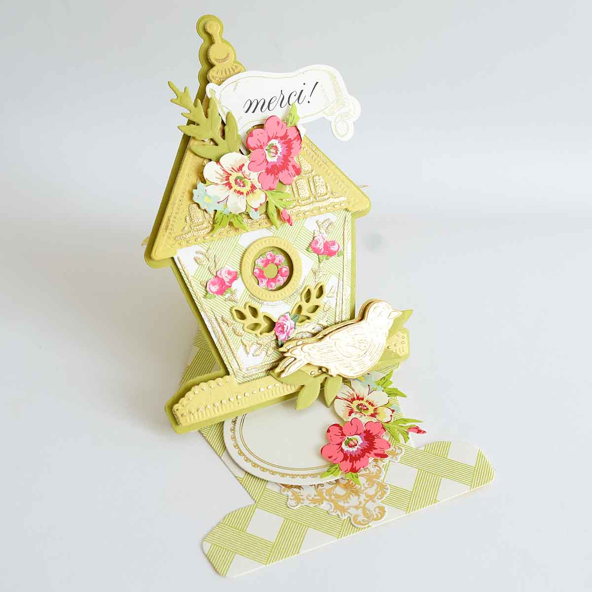 a card with a birdhouse and flowers on it.