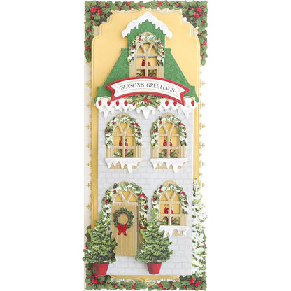a christmas card with a house and wreath.