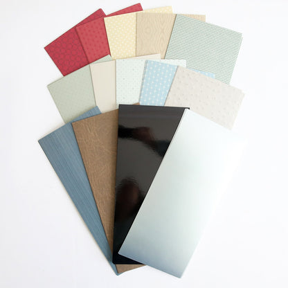 A pile of Classic Car Cardstock in different colors on a white surface.