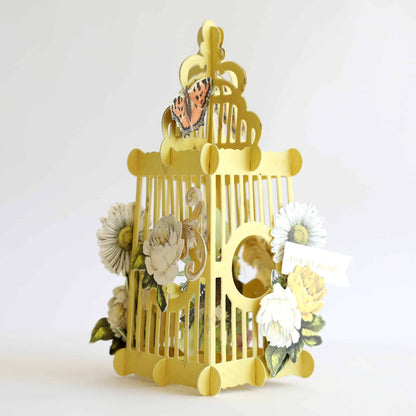 a yellow birdcage with flowers and a butterfly on it.