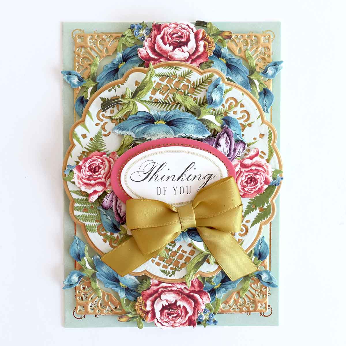a handmade card with a gold bow on it.