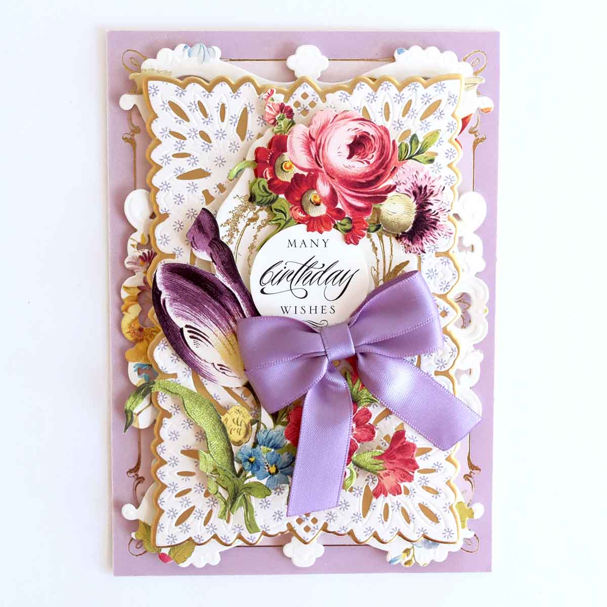 a card with a purple ribbon and flowers on it.