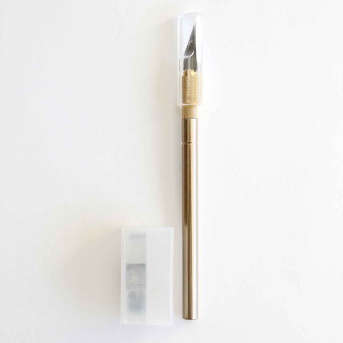 a gold colored pen with a white eraser next to it.