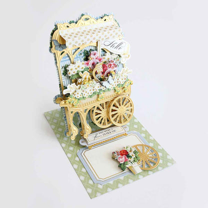 a card with a miniature carriage with flowers on it.
