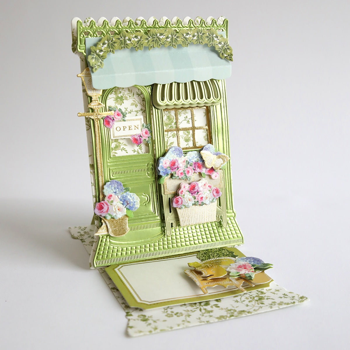 A small green Flower Shop 3D Easel Dies building with flowers on it.
