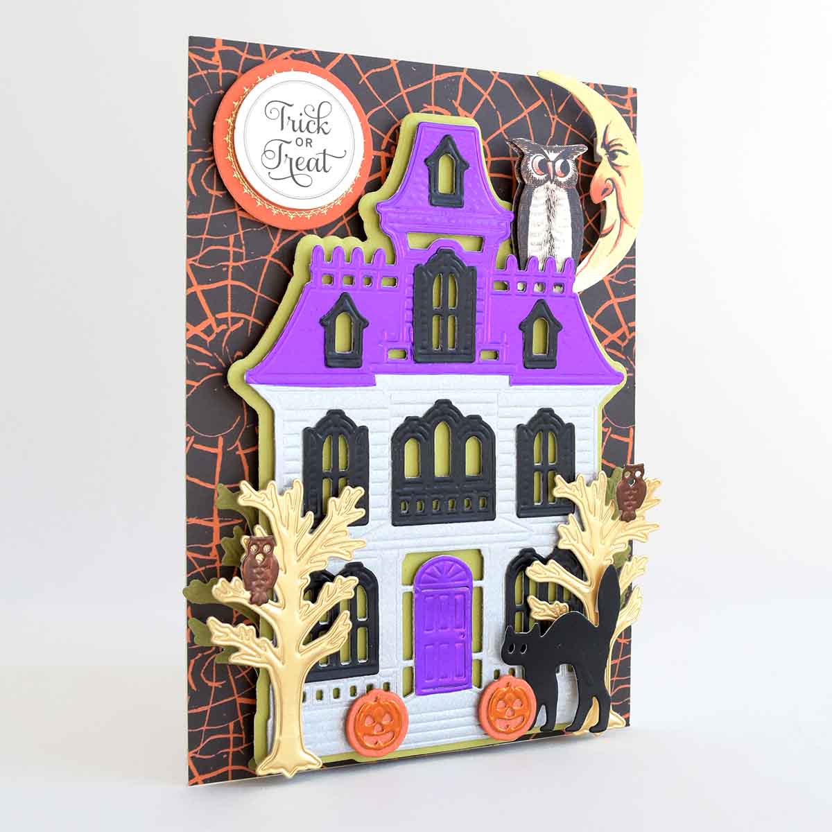 a halloween card with a house and a cat.