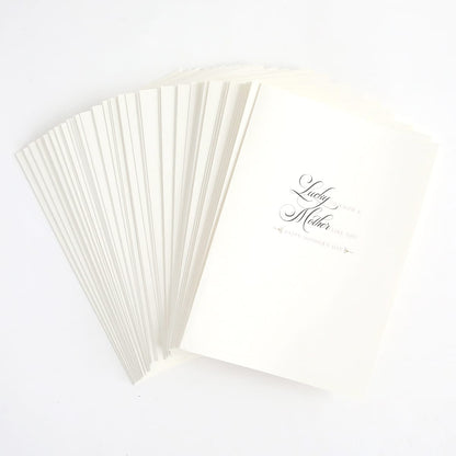 a stack of white folded cards with a black ink pen.