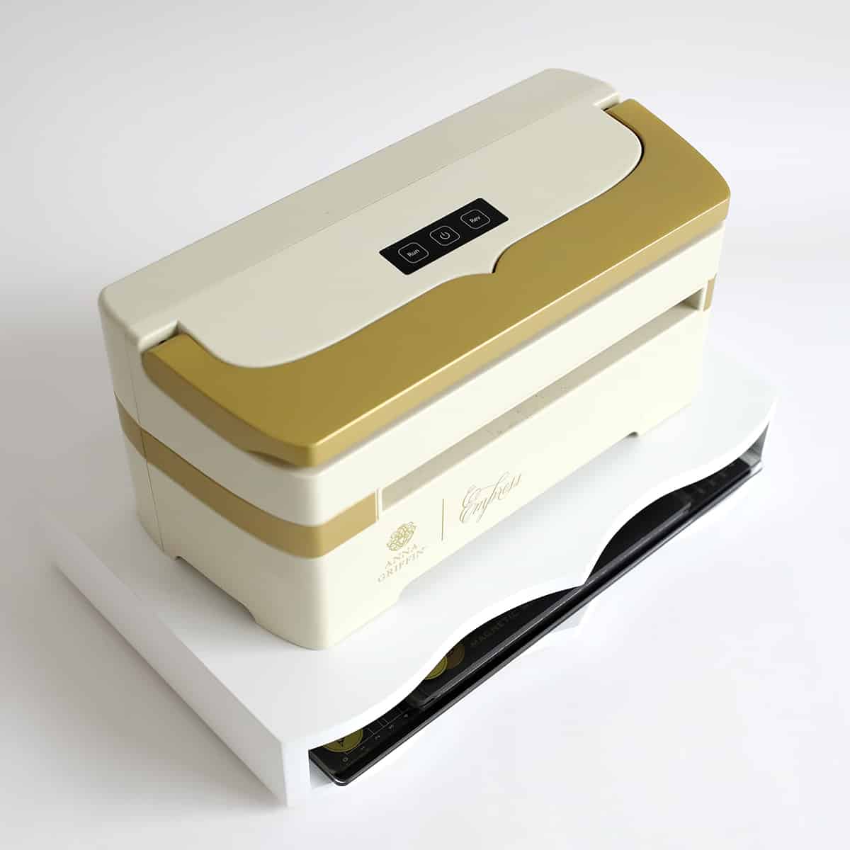 a white and gold lunch box sitting on top of a white box.