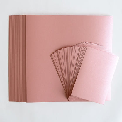 a stack of pink cards sitting on top of a white table.