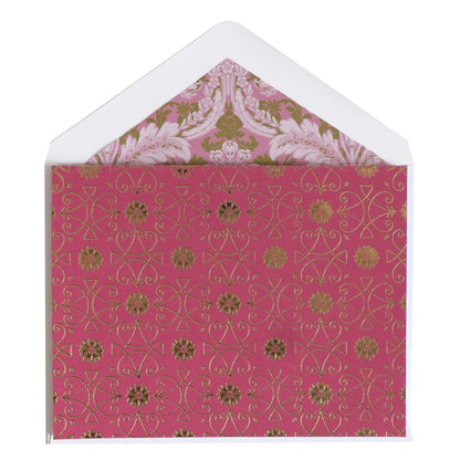 a pink and gold card with a white envelope.