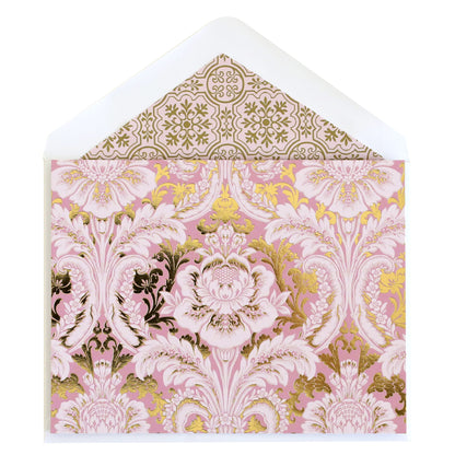 a pink and gold card with a white envelope.