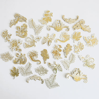 a bunch of gold and silver brooches on a white surface.