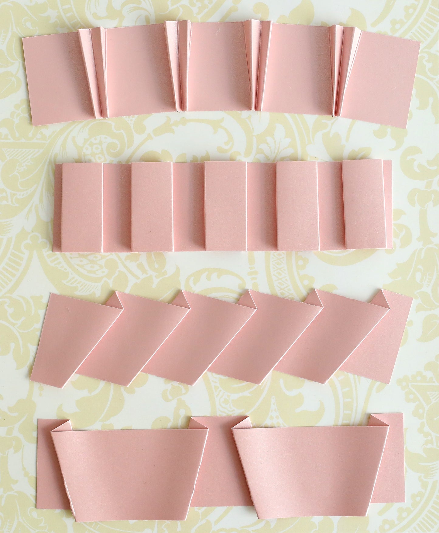 several pieces of pink folded paper on a table.