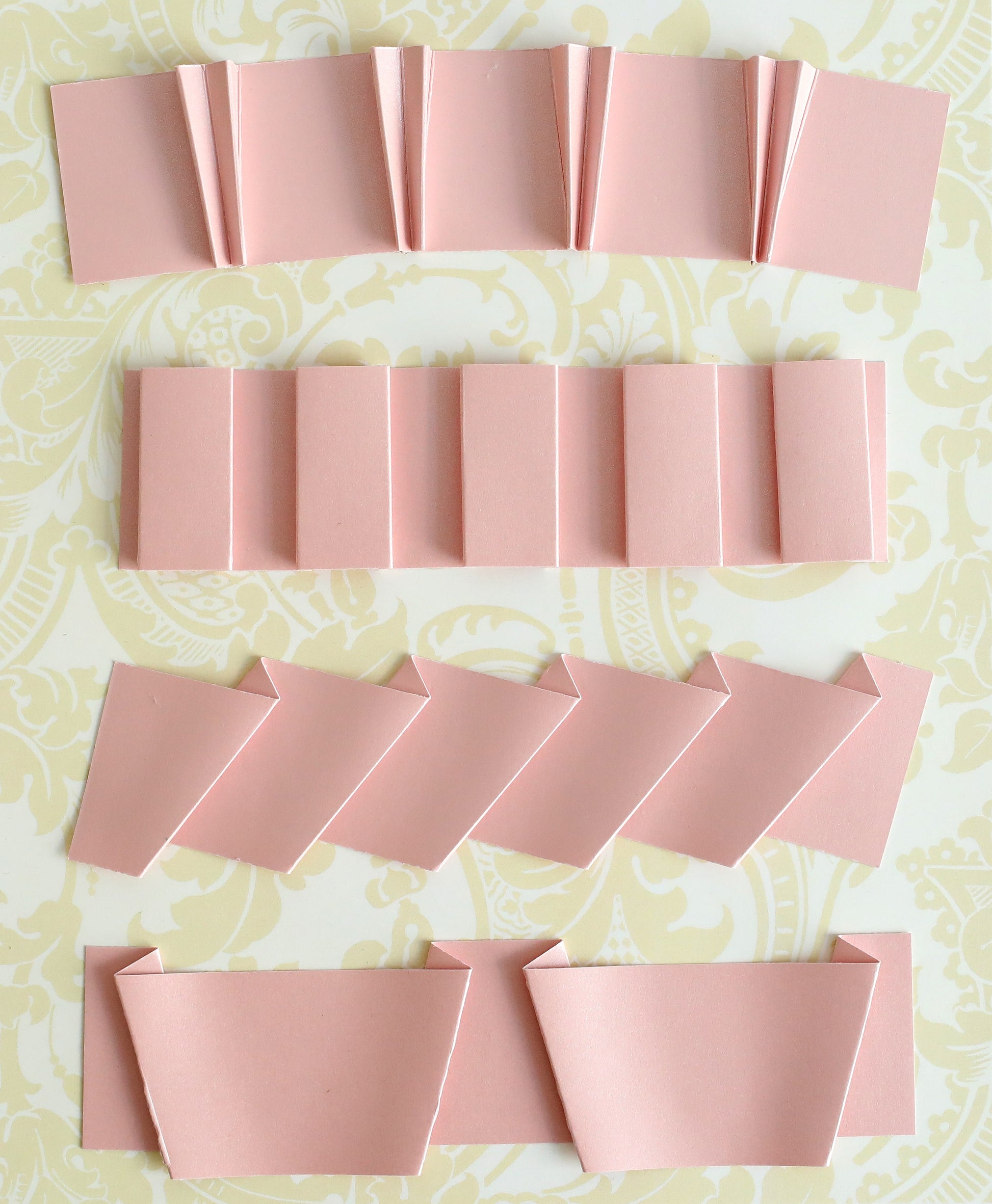 several pieces of pink folded paper on a table.