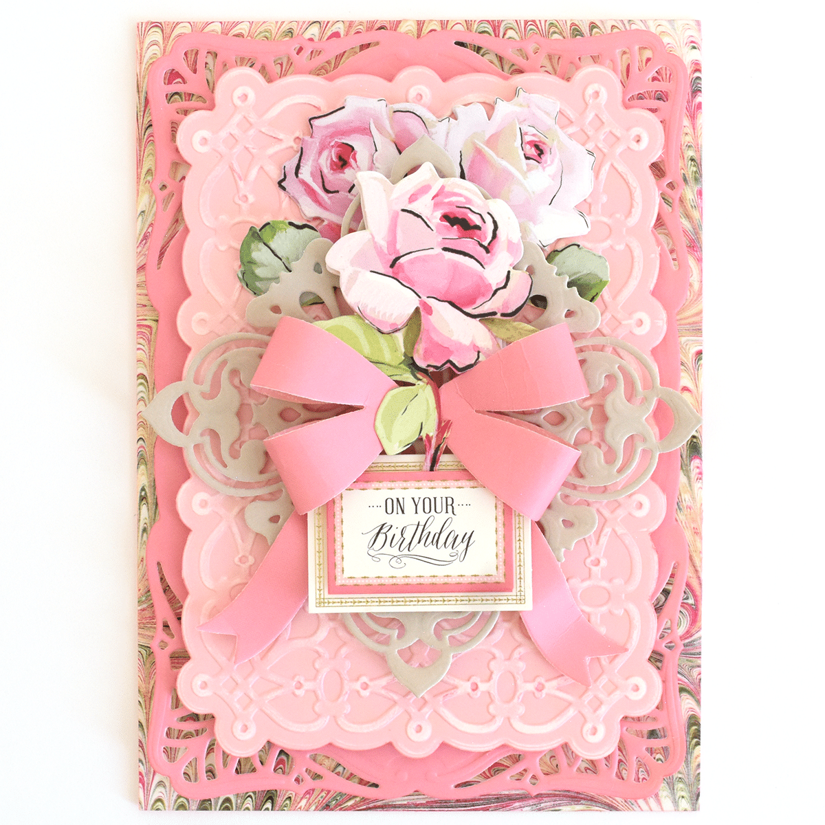 a pink card with a pink bow and flowers on it.