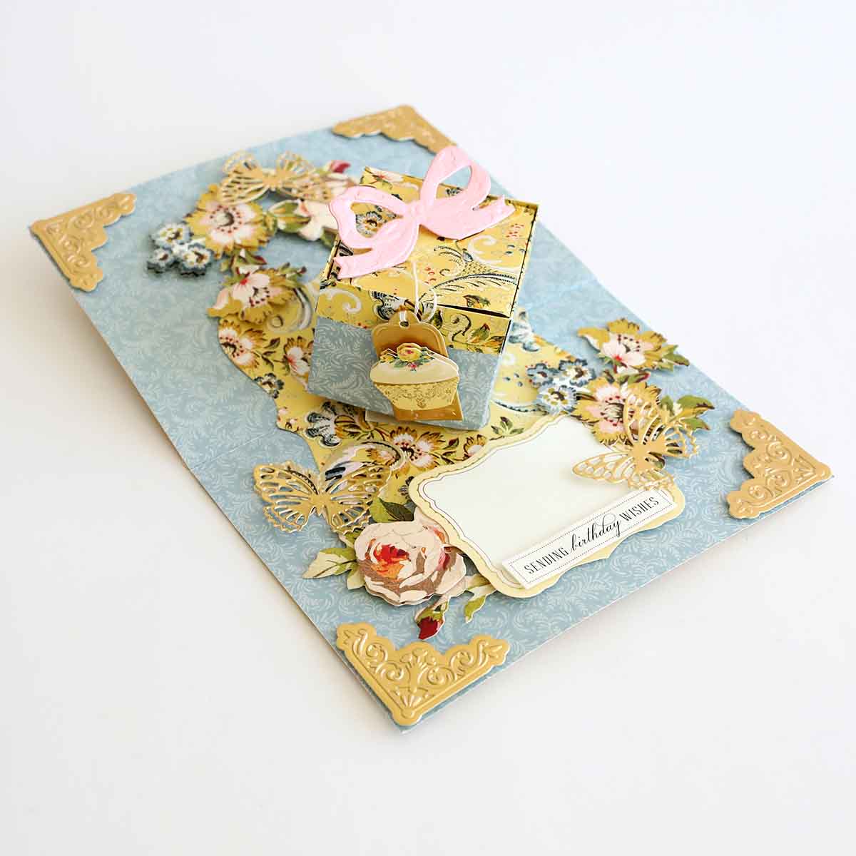 a blue and gold card with a pink ribbon.