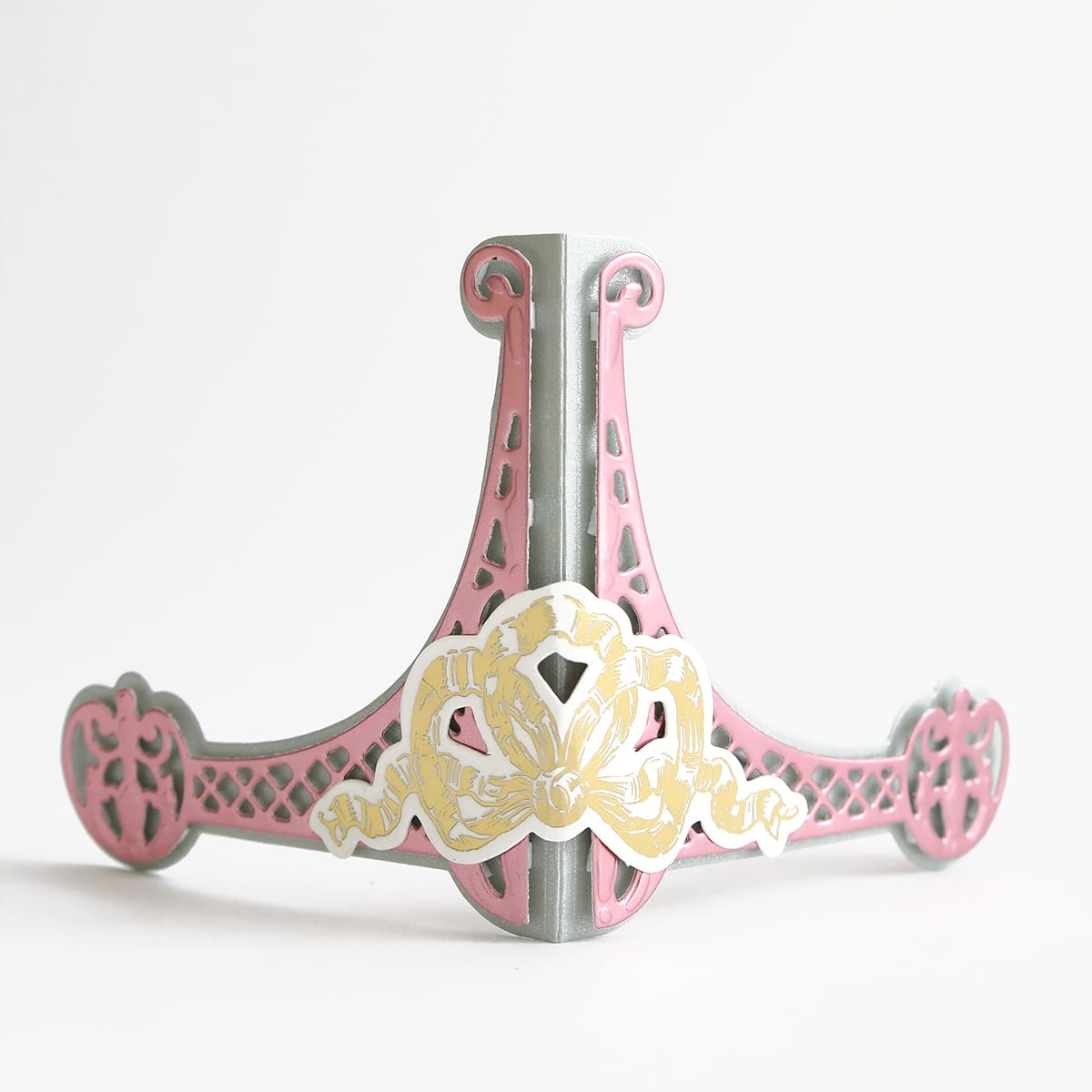 a pink and gold decorative object on a white background.