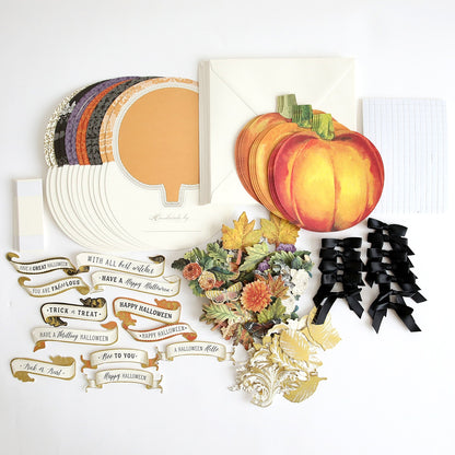 A collection of Simply Rocking Pumpkin Card Making Kits, paper, and pumpkins on a white surface.