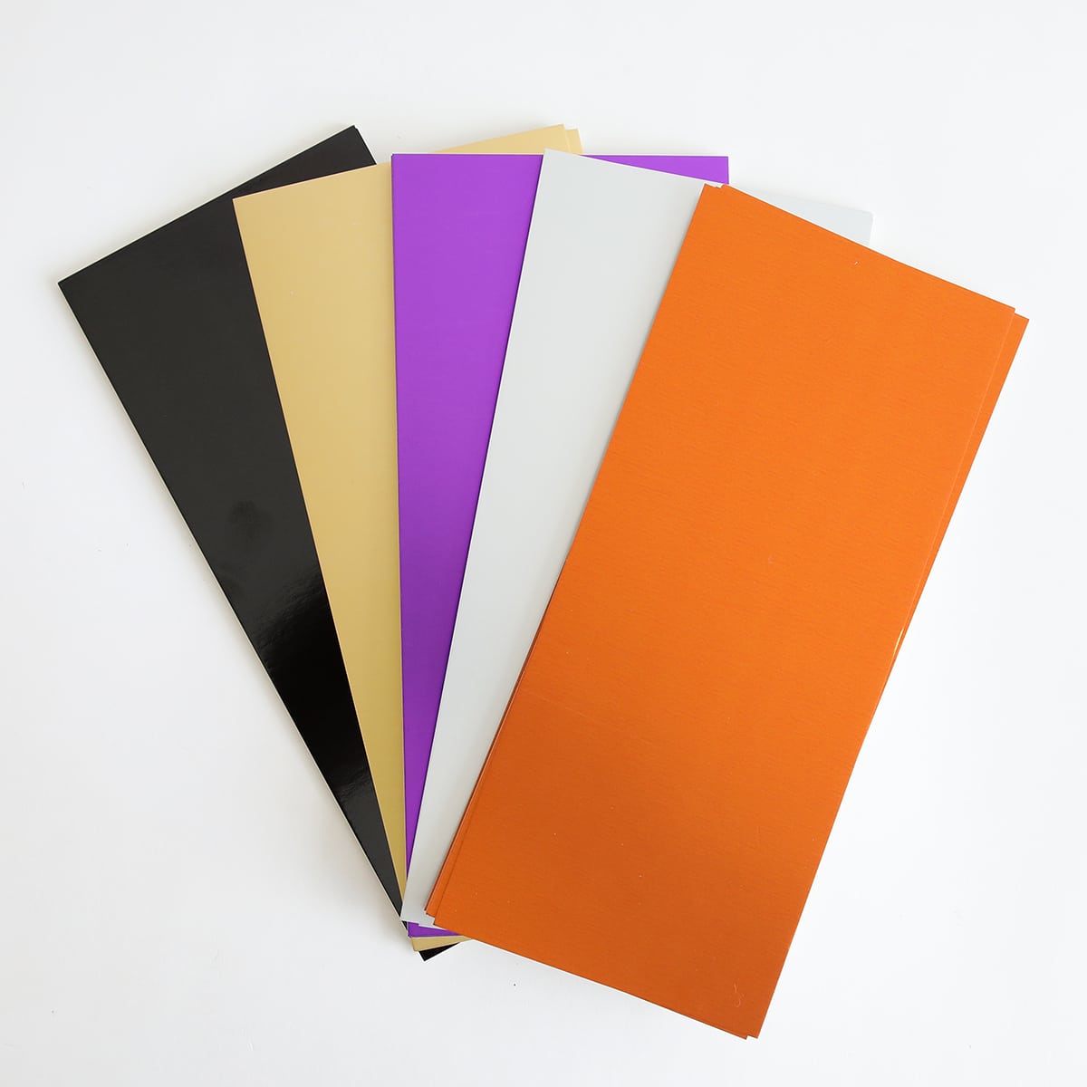 five different colors of paper on a white surface.