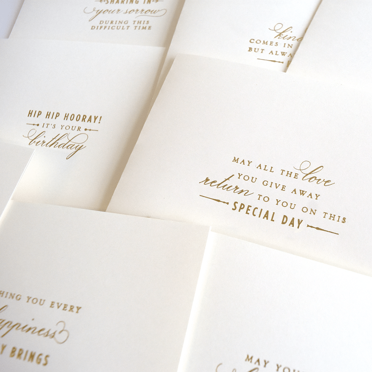 a pile of white cards with gold foil on them.
