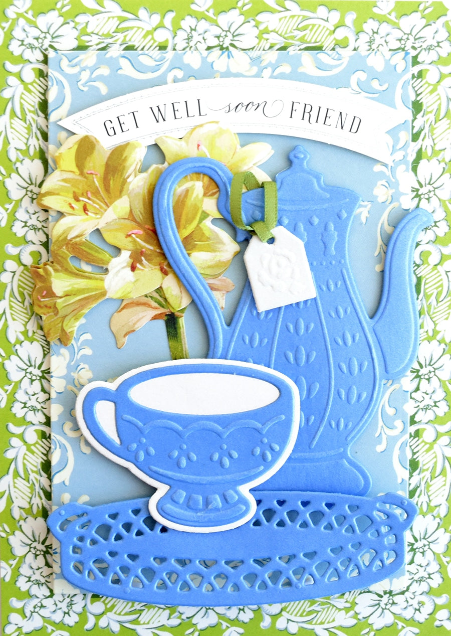 a card with a blue teapot and yellow flowers.