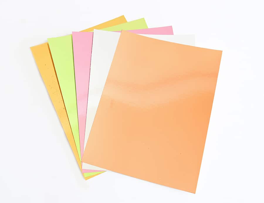 a stack of different colored papers on a white surface.